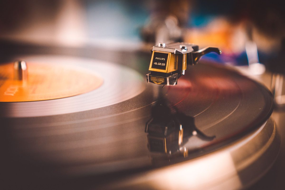 Close-up of a black vinyl record playing on a vintage gold turntable.